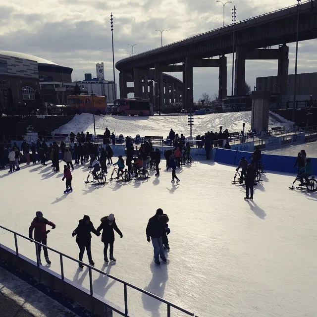 Skaters and ice bikes on the Canalside rink under the Skyway on a bright winter day